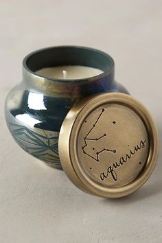 a candle that is sitting next to a vase with the word aquarius on it