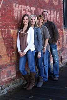 a group of people standing in front of a brick wall with the words west virginia painted on it