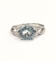 a blue and white diamond ring sitting on top of a white surface with diamonds around it