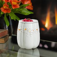 a white candle holder sitting on top of a table next to a vase filled with flowers