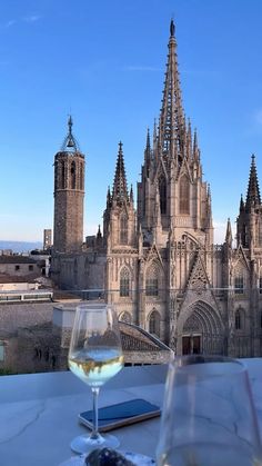 a glass of wine on a table with a view of a cathedral in the background