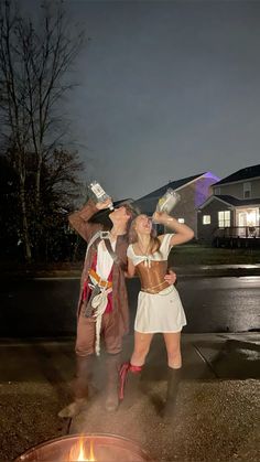 two people dressed in costumes standing next to a fire pit