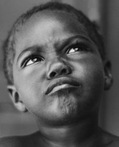 a black and white photo of a young boy looking up at something in the air