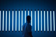 a person standing in front of a blue wall with several lights hanging from it's sides