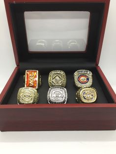 four different rings in a wooden box with glass inserts on the top and bottom