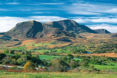 the mountains are covered in green grass and trees