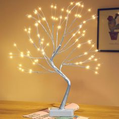 a lighted tree is sitting on top of a table with a book and pen in front of it