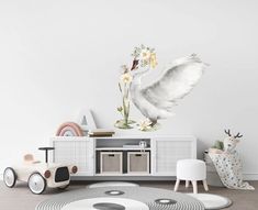 a white swan flying over a wooden floor next to a wall with flowers on it