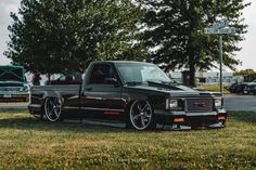 a black truck parked on top of a lush green field