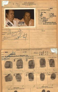 two men are looking at an old handprint document with multiple finger prints on it