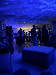 a group of people standing in a living room under a blue sky filled with stars