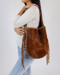 This is a beautiful Argentinian Cowhide Leather Hobo Shoulder Bag with fringe, brown in color.  Artisan Made. It has and inside pocket with a key ring clasp, and a magnetic closure.  It is approximate 11 inches by 13 inches long, and 2.25 inches wide.  The strap is approximate 1.75 inches wide.  Fringes are approximate 8.5 inches long.  This bag is completely handmade from beginning to end.  Please note natural leather can have markings.   Each product comes inside a cotton bag with logo so you can use it to storage Because this product is one of a kind, I do not accept cancellations, returns or exchanges, but if you have a problem with the order, please do not hesitate to contact me.  Thank You. Brown Fringe Bag For Everyday Use, Leather Hobo Bag With Tassels In Tote Shape, Leather Hobo Bag With Tassels, Leather Hobo Shoulder Bag With Tassels, Artisan Brown Hobo Tote Bag, Leather Fringe Hobo Bag For Daily Use, Brown Leather Shoulder Bag With Fringe, Bohemian Brown Bucket Bag With Tassels, Daily Use Leather Hobo Bag With Fringe