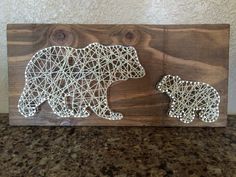 two bears made out of string sitting on top of a wooden board with a marble countertop