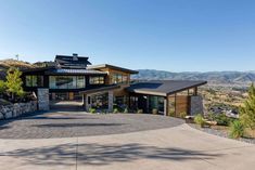 a large house on top of a hill with mountains in the background