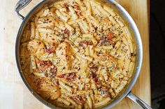 a pan filled with pasta and sauce on top of a wooden table