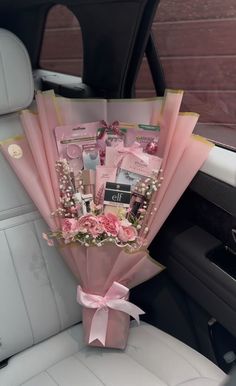 a bouquet of flowers sitting in the back seat of a car, wrapped in pink paper