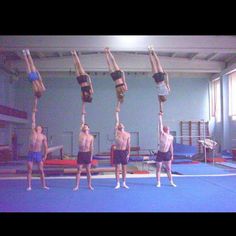 six men doing acrobatic tricks in an indoor gym