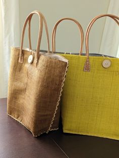 This is a super fun oversized bag that is made of woven raffia straw.  The bag has a great structured shape that will keep its form thanks to the double layer of straw. Made in Madagascar. Size: base of the bag - 11 x 5 inches, opening of the bag 22 inches. The height of the bag is 14 inches. Leather handles Cotton fabric with drawstring to keep things safe and secure Inner pocket Wooden button with a string loop for additional closure and design Yellow Woven Bag With Double Handle, Woven Burlap Tote Straw Bag, Yellow Woven Double Handle Bag, Summer Burlap Tote Bag, Burlap Straw Bag For Beach In Summer, Summer Beach Burlap Straw Bag, Beach Shoulder Bag In Natural Burlap, Yellow Woven Beach Bag For Shopping, Yellow Straw Shopping Bag With Double Handle