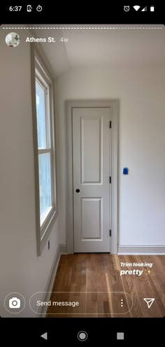 an empty room with a white door and window in the center is seen on this phone screen