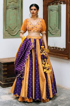 Mustard, purple colorblock attached cancan lehenga with bandhani and geometric print. Paired with floral, barfi pattern embroidered padded blouse and dual colored dupatta with shell tassel.
Components: 3
Pattern: Digital Print, Embroidery
Type Of Work: Bandhani, geometric
Neckline: V neck
Sleeve Type: Half
Fabric: Silk, Chanderi
Color: Yellow,Purple
Other Details: 
Pleated sleeves
Scallop bordered dupatta
Shell tassel bordered blouse
Side tassel latkan
Back criss cross detailing
Attached layered Pola Blus, Chaniya Choli Designs, Simple Lehenga, Printed Lehenga, Trendy Outfits Indian, Outfits Indian, Indian Outfits Lehenga, Lehenga Designs Simple, Indian Bride Outfits