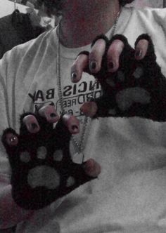 a woman with black and white nails holding up two pairs of fake paw prints on her hands