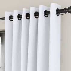 white curtains hanging on the side of a window with black hardware and curtain rods in front of them