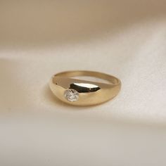 a gold ring with a diamond on it sitting on a white cloth covered tablecloth