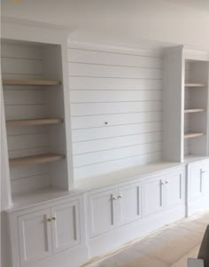 an empty room with white cabinets and shelves