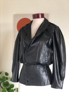 Vintage Alicia Herrera black leather jacket 80s designer 1980s bat wing goth witch gothic witchy vamp peplum waist fitted S/XSSuch a rare find!! The details and craftsmanship of this jacket is truly stunning!! Bikercore meets New Wave!SEXY AS HELL!The Oshwahkon company was started by Alicia Herrera and her husband in the Soho area of NYC in 1971. Their leather creations are considered to be highly collectible. Worn by rockstars, celebrities, through the 70s & 80s. >> Please double check your measurements & compare to these listed below, for accurate sizing. Vintage often runs small, so don’t rely on the tag size. Tag reads: Alicia Herrera New York>>> Measurements taken flat/unstretched :*Chest Width, armpit to armpit: approx 18” (36”)Bust a bit lower: 17” (34” )*Shoulder seam to shoulder s Fitted Gothic Leather Jacket For Parties, Gothic Fitted Leather Jacket For Fall, Vintage Black Biker Jacket For Alternative Fashion, Fitted Gothic Leather Jacket For Fall, Vintage Fitted Long Sleeve Biker Jacket, Vintage Fitted Biker Jacket With Long Sleeves, Fitted Vintage Biker Jacket With Long Sleeves, Goth Witch, Black Leather Motorcycle Jacket