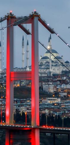 a large bridge with some lights on it and buildings in the backgrouds