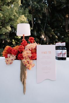 the table is set up with an orange and pink flower arrangement on top of it