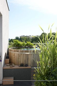 a wooden hot tub sitting next to a lush green field