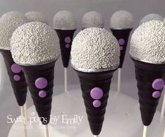 there are some cupcakes with white and purple frosting on sticks in the shape of cones