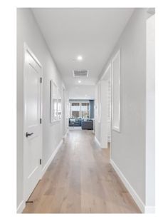 an empty hallway with white walls and wood floors