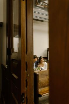 two people sitting at a table in front of a door and looking into the room