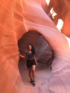 a woman standing in the middle of a slot in an antelope like area