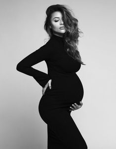 a pregnant woman posing for a black and white photo with her hands on her hips