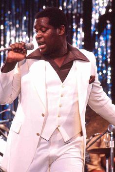 a man in a white suit singing into a microphone