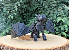 a black dragon figurine sitting on top of a tree stump