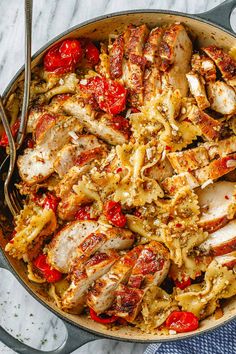 a skillet filled with chicken, tomatoes and pasta