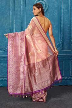 Look your best at weddings and festive occasions in this beautiful golden pink Banarasi saree with purple zari border. It comes with a matching blouse piece. Disclaimer: The shown stitched blouse on the model is for display purpose only. The saree comes with a matching blouse piece and finished with fall and piko. Pink Bollywood Pre-draped Saree With Meenakari, Designer Pink Paithani Silk Lehenga, Designer Pink Paithani Silk Pre-draped Saree, Pink Meenakari Pre-draped Saree, Pink Pre-draped Meenakari Saree, Festive Pink Pre-draped Saree With Meenakari, Purple Tissue Silk Traditional Wear With Zari Weaving, Pink Pre-draped Saree With Zari Weaving In Tissue Silk, Pink Meenakari Art Silk Pre-draped Saree