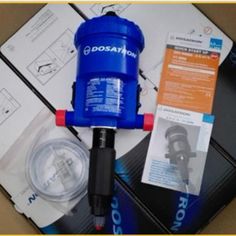 a blue water pump sitting on top of a box next to some papers and other items