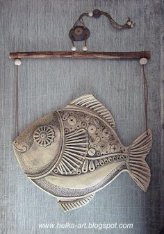 a metal fish hanging on a wall next to a wooden frame with an iron hook