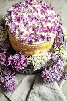 a cake with purple and white flowers on it sitting on top of a black plate