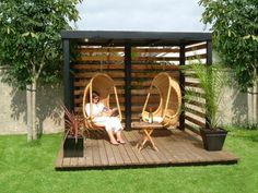 a woman sitting in a chair on top of a wooden deck next to a potted plant