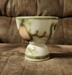 a green and white bowl sitting on top of a brown chair next to a couch