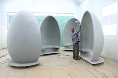 a man standing in front of three white oval shaped objects on top of a hard wood floor