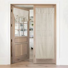 an open wooden door with a white curtain