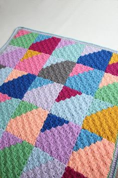 a multicolored crocheted blanket is laying on the floor