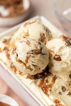 three scoops of ice cream in a white dish with caramel and pecans